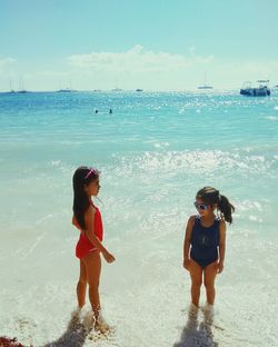 High angle view of siblings talking while standing on shore at beach against sky