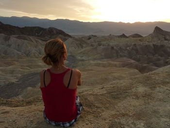 Rear view of woman looking at mountains during sunset