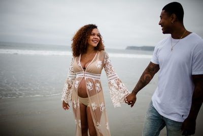 Mixed race couple smiling & walking on beach