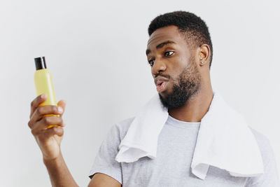 Side view of young man using mobile phone against white background