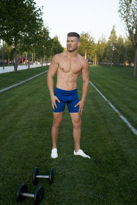 Portrait of shirtless man exercising on field