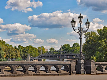 Lamp post on bridge over river against sky