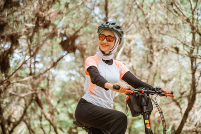 Smiling young woman on bicycle at park