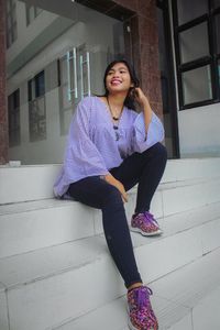 Portrait of young woman sitting on wall