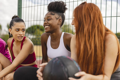 Happy friends having fun sitting in sports court