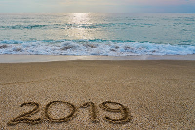 Text on sand at beach against sky