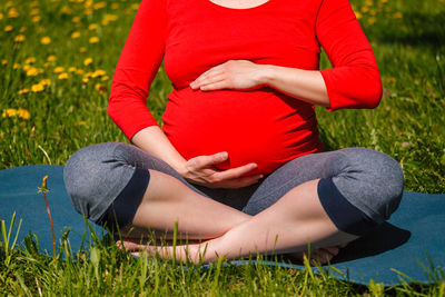 Pregnant woman doing asana sukhasana outdoors
