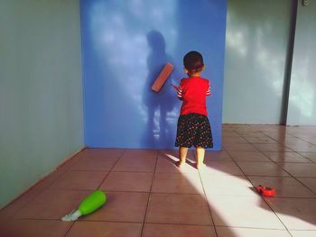 Rear view of boy painting wall at home