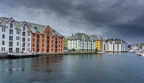 Buildings by river against sky in city