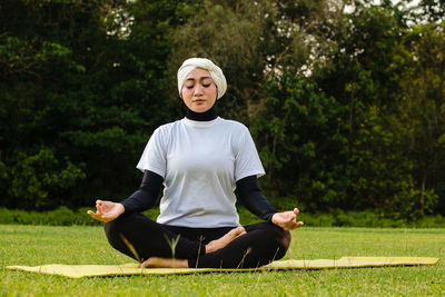 Attractive woman in hijab training in park, meditating.  healthy lifestyle