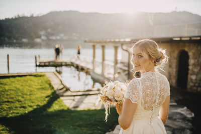 Young woman with umbrella standing by water