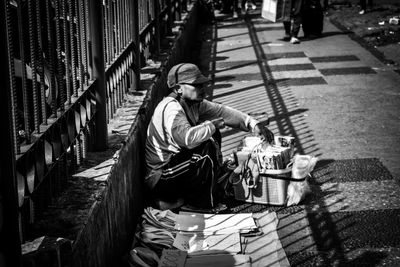 Side view of man selling books and bags on footpath