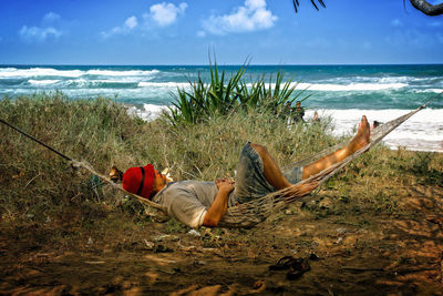 Man lying down on beach against sky