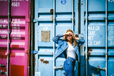 Full length of young woman standing against building