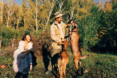 A man with a beard on small farm feeds nubian goats on sunny, peaceful day