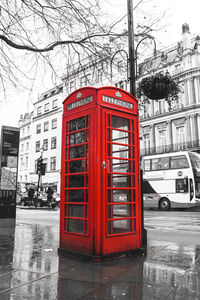 Red telephone booth on road in city