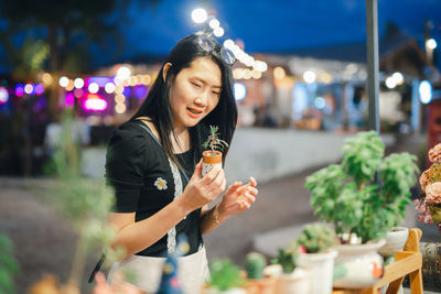 Young woman standing against illuminated city at night