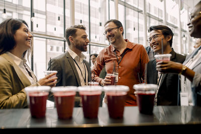 Happy male and female business delegates enjoying drinks during break at convention center