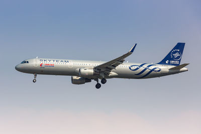 Low angle view of airplane flying against clear blue sky