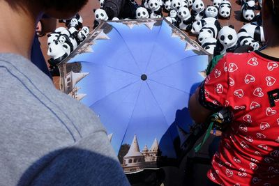 Cropped image of people with umbrella and toy pandas