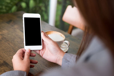 Midsection of woman holding smart phone in cafe