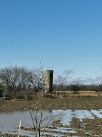 Built structure on field against clear blue sky