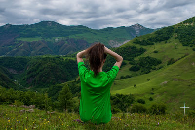 Rear view of woman with arms raised against mountain range