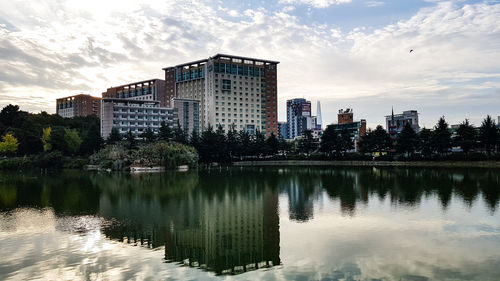 Reflection of buildings in lake against sky in city