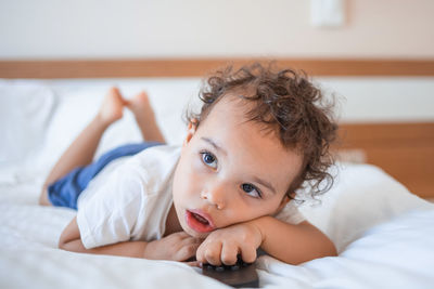 Portrait of cute baby boy lying on bed at home