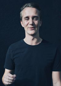 Portrait of young man standing against black background