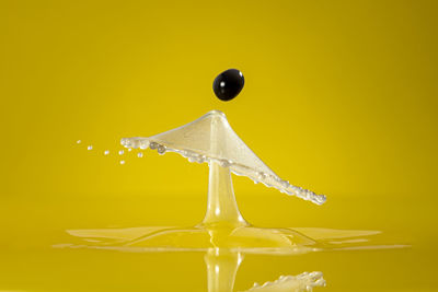 Close-up of water drops on glass against yellow background