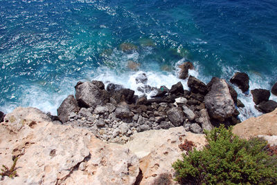 High angle view of waves splashing on rocks at shore