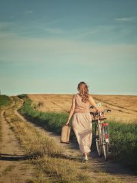 Rear view of woman riding bicycle on field