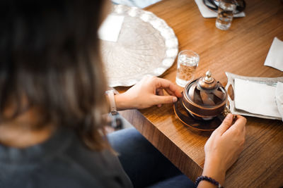 High angle view of woman holding coffee cup on table