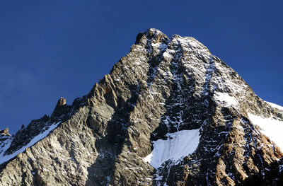 Low angle view of rocky mountains against cloudy sky