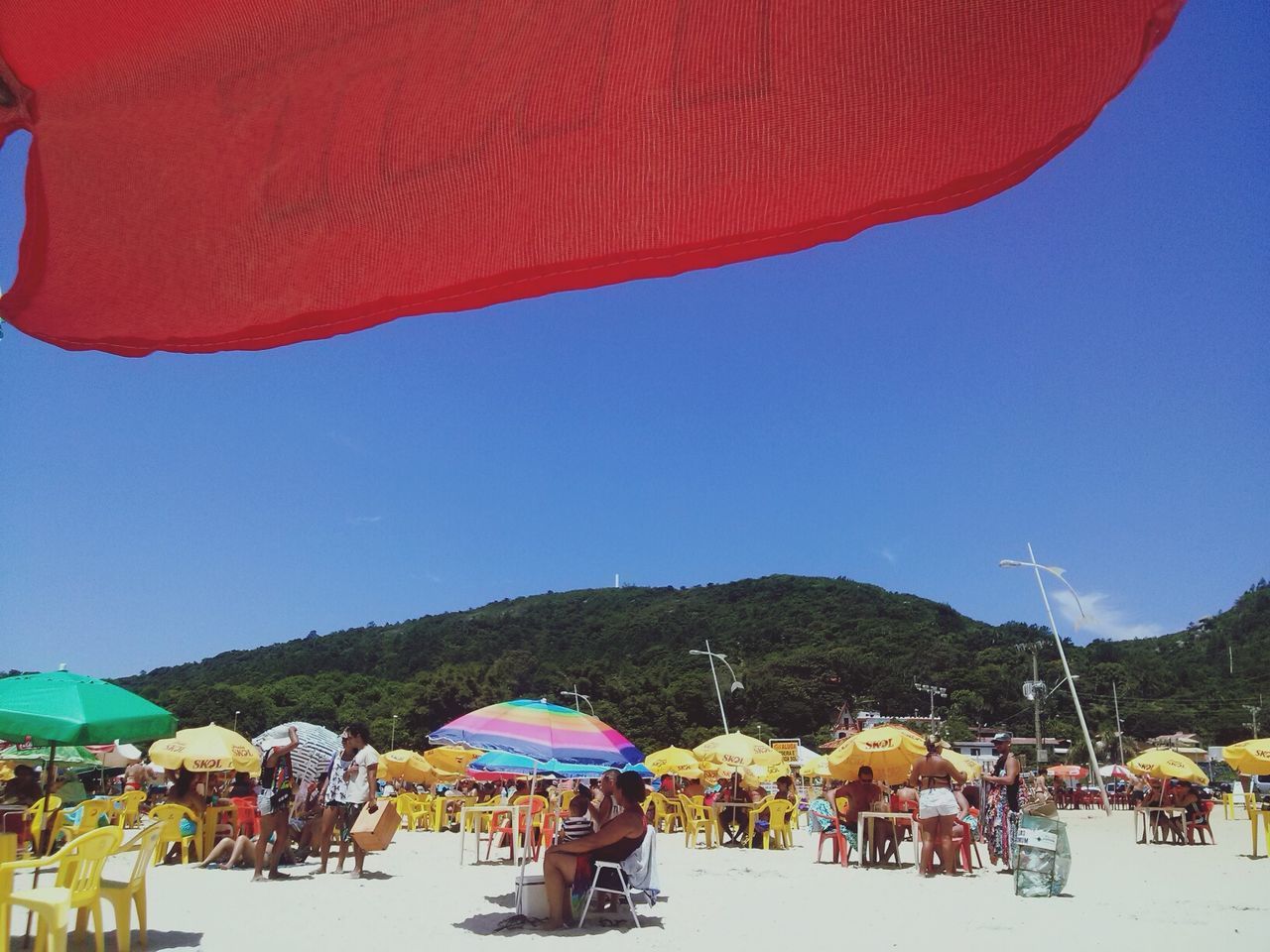 lifestyles, leisure activity, clear sky, person, men, blue, large group of people, vacations, mountain, rear view, beach umbrella, copy space, tourist, sky, parasol, sitting, tourism, casual clothing, relaxation