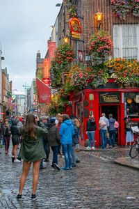 Rear view of people walking on street against buildings