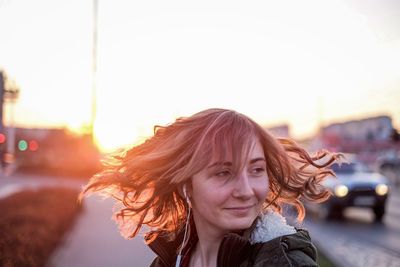Portrait of young woman in city during sunset