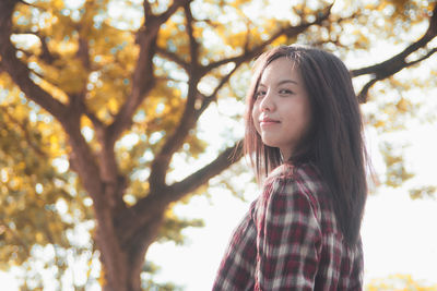 Portrait of smiling young woman against trees