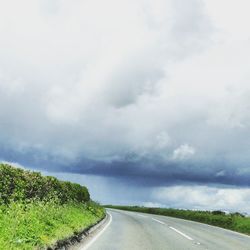 Country road against cloudy sky