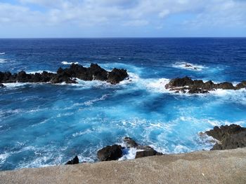 Scenic view of blue sea and rocks against sky