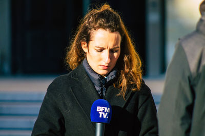 Portrait of young woman with text standing outdoors