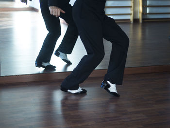 Low section of man dancing on hardwood floor at studio