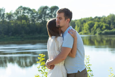 Couple embracing while standing by lake