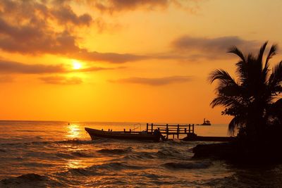 Silhouette boat moored on sea against sky during sunset