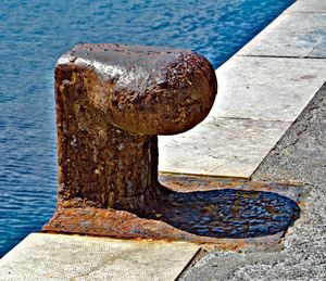 Close-up of rusty metal on wood at harbor