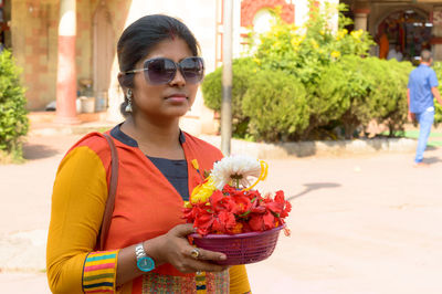 Bengali woman holding a bucket of religious offering flowers during durga puja celebration.