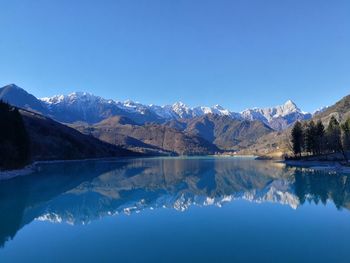 Scenic view of lake and mountains against blue sky