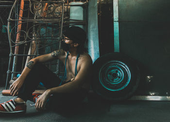 Side view of young man sitting on flooring