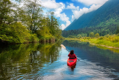 Rear view of man on boat in lake against sky